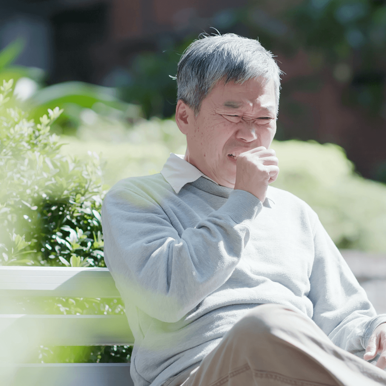 Senior man coughing, displaying symptoms of RSV, a respiratory infection affecting older adults in Singapore.